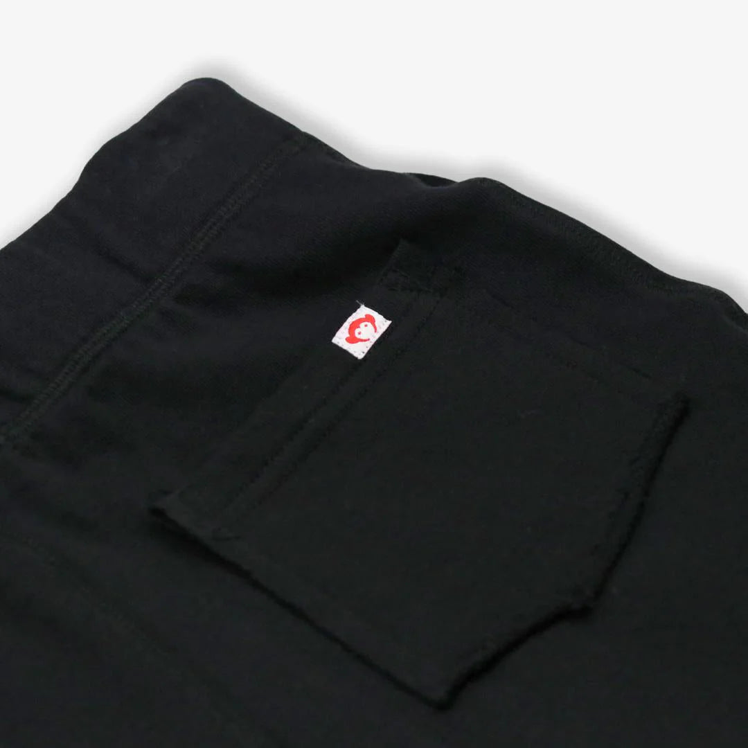 Black pants with a red and white logo on the pocket against a white background