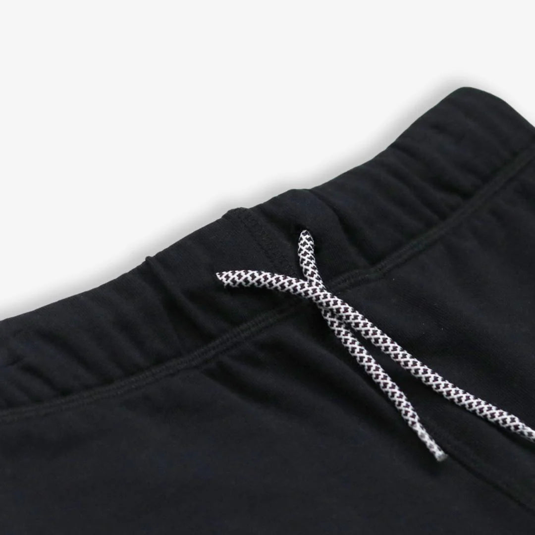 Black pants with a braided drawstring on a light gray background