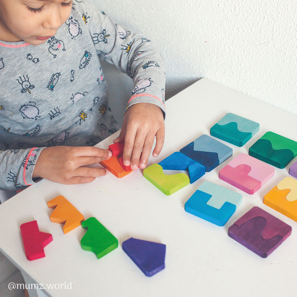 Child playing with colorful geometric shapes on a white surface