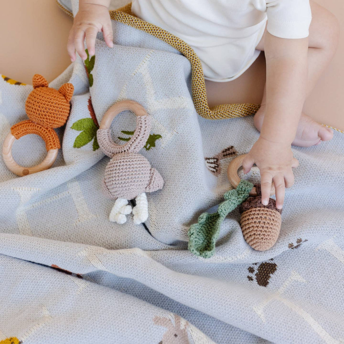 Baby playing with crocheted toys on a soft surface