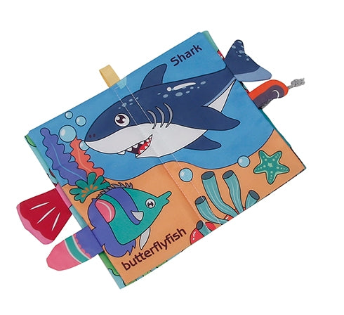 A colorful children's fabric book or soft toy with a shark and butterflyfish design, shown on a plain white background.