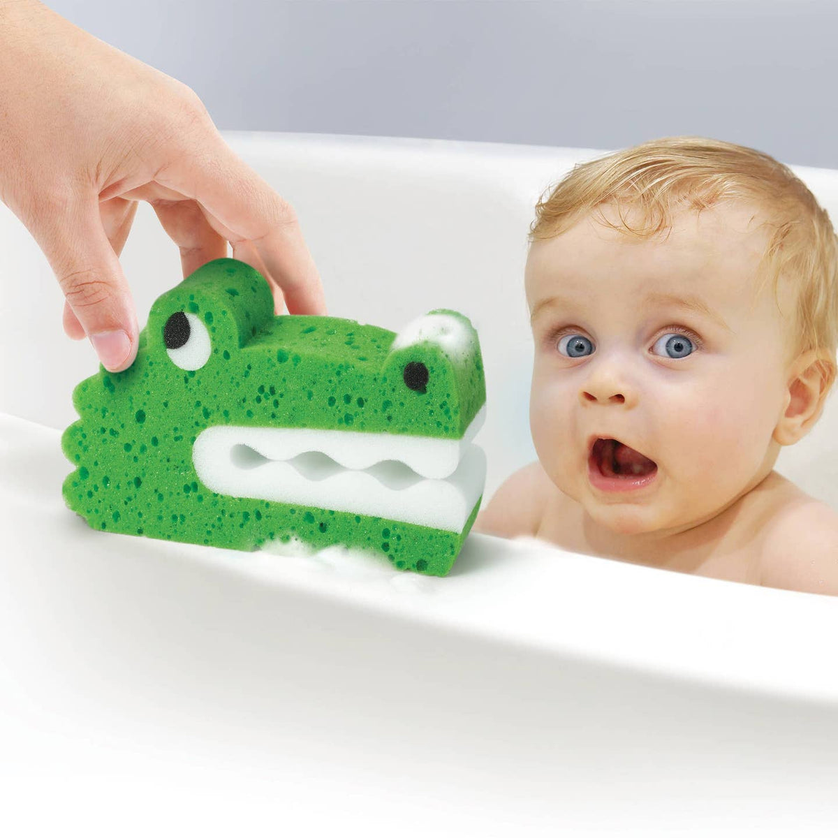 Baby in a bathtub with a green frog-shaped bath toy