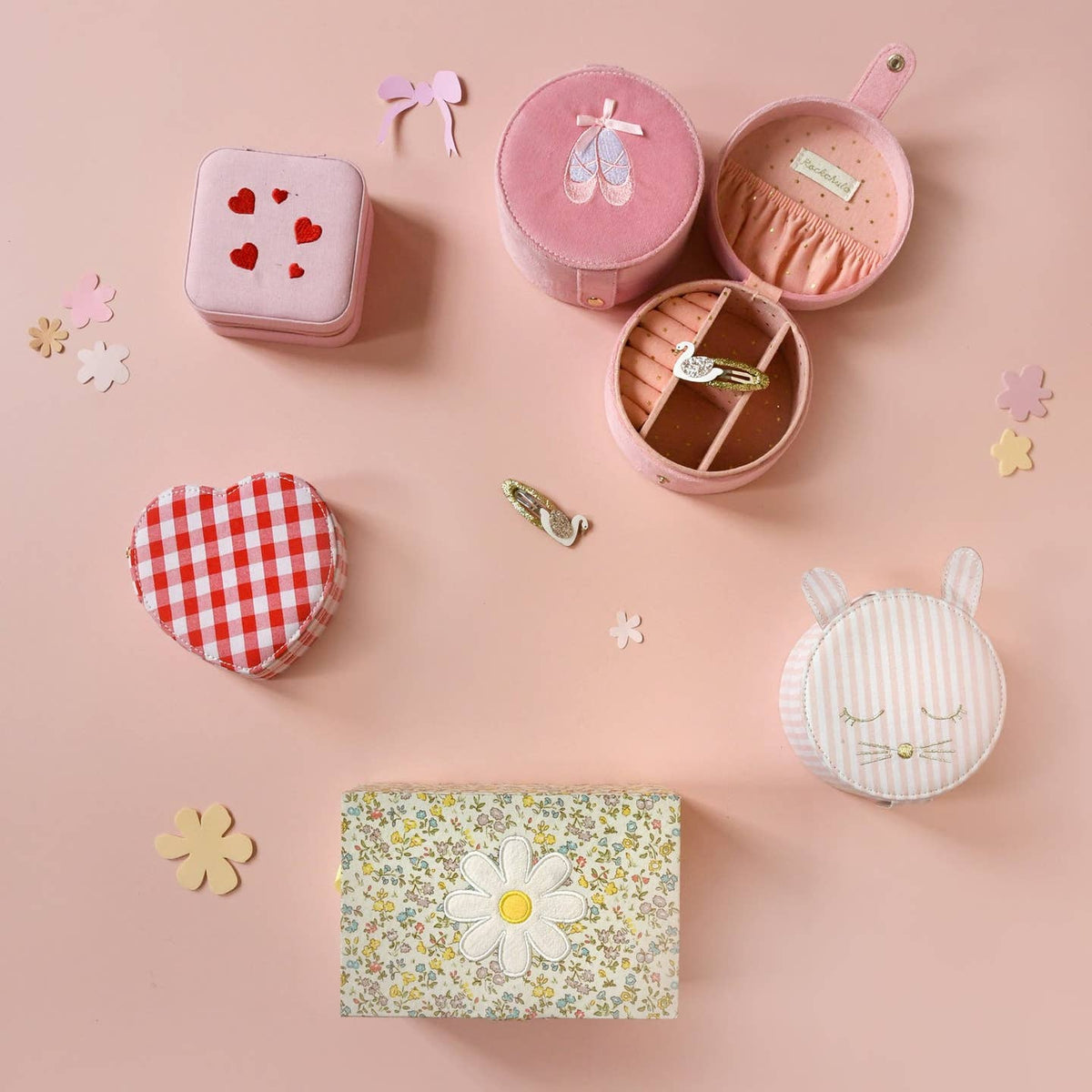 Collection of small, round jewelry boxes with different designs on a pink background