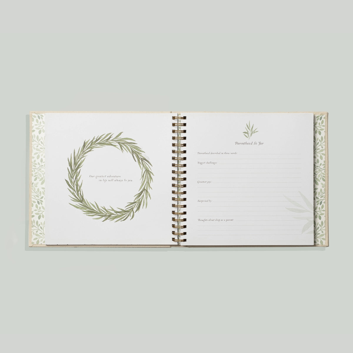 Open book with decorative wreath design on a light gray background