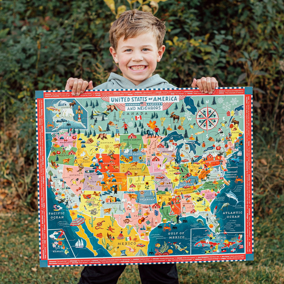 Child holding a colorful map of the United States and Canada outdoors.
