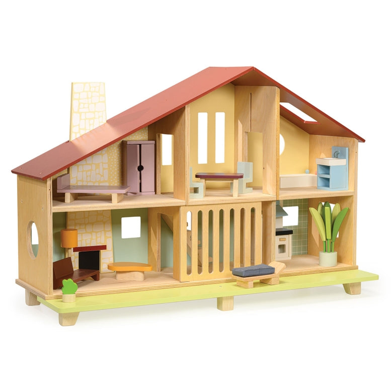 Wooden Cedar Chalet Modernist Dollhouse by Mentari featuring a mid-century modern architectural design with an open-front layout, a red gabled roof, a pebble-dash style chimney breast, and six furnished rooms complete with a starter set of modernist furniture and a sliding ground-floor grill opening onto an urban lawn with a potted plant and bench.