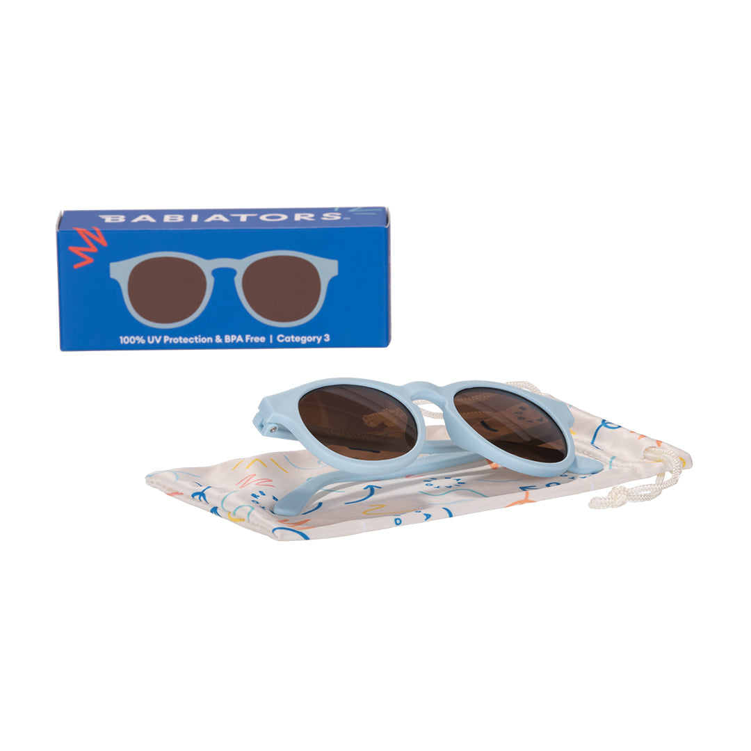 Children's sunglasses with blue case and Babiators box on a white background