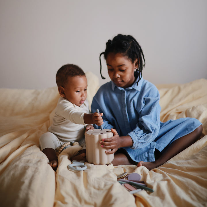 Two children playing with a toy on a bed.