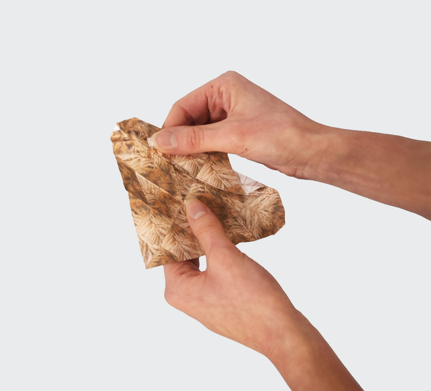Hand holding a crumpled brown paper bag against a white background