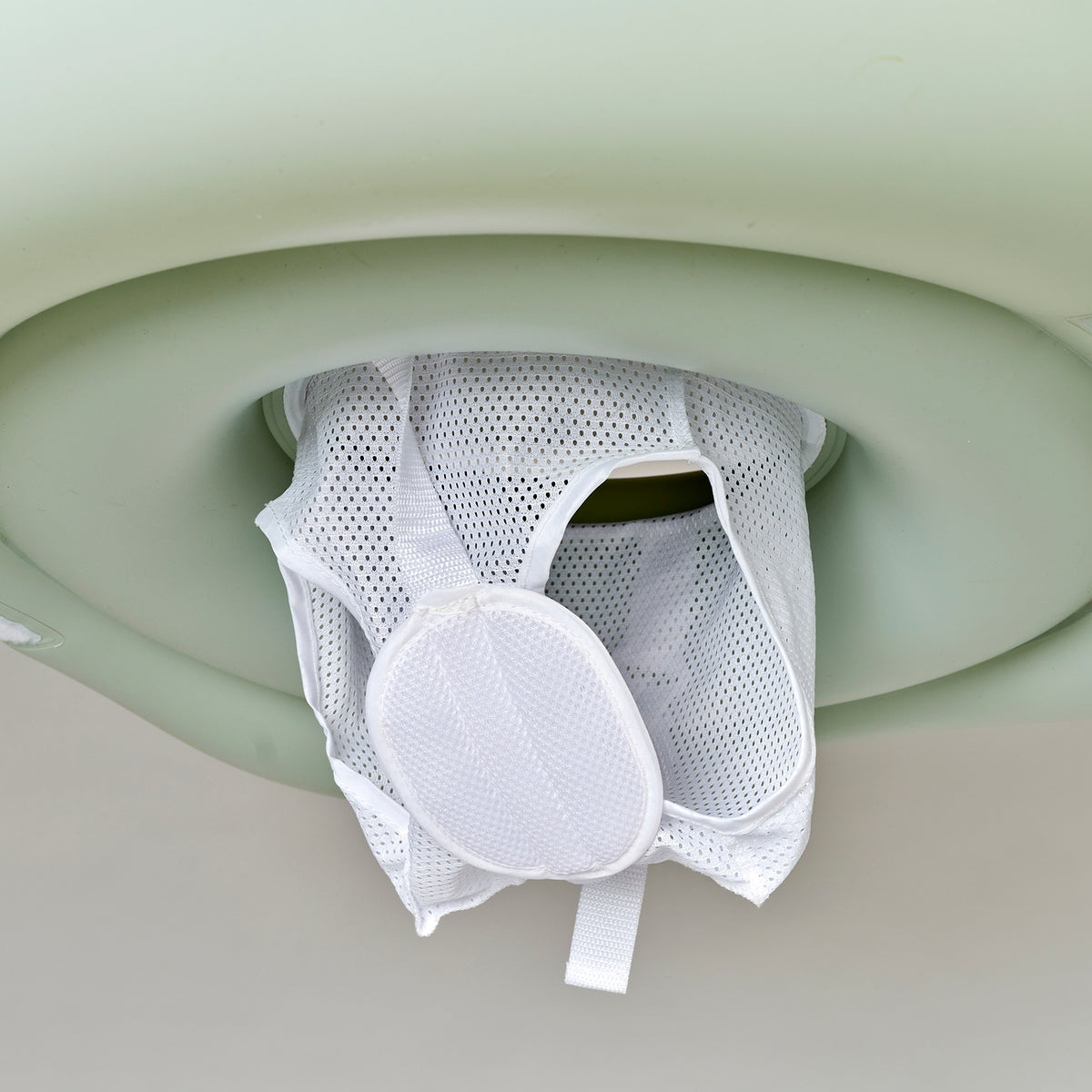 White mesh product hanging from a green plastic holder against a light background