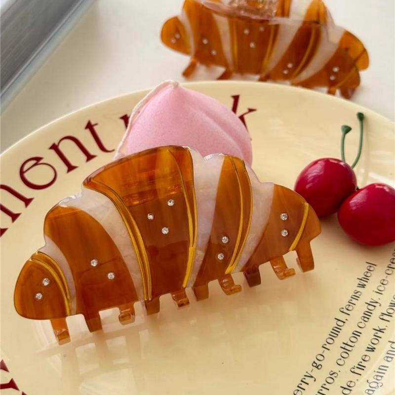 Decorative hair clip shaped like a tiger with pink and white accents on a plate.