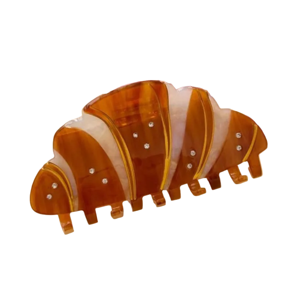 A crescent-shaped hair claw clip made of amber and cream marbled resin, accented with small rhinestones, shown on a plain white background.