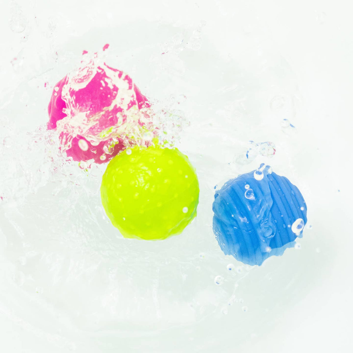 Three colorful bath bombs溶解在水中,产生气泡。