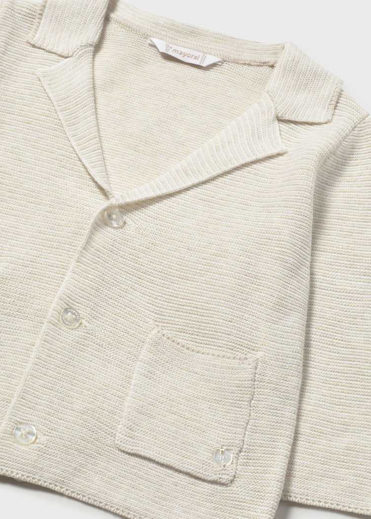 Close-up of a beige knitted cardigan with a brand label on a white background