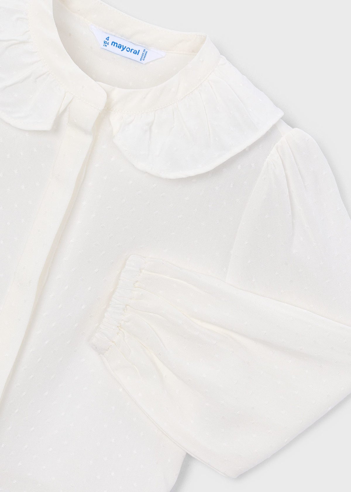 White blouse with a ruffled collar on a light gray background