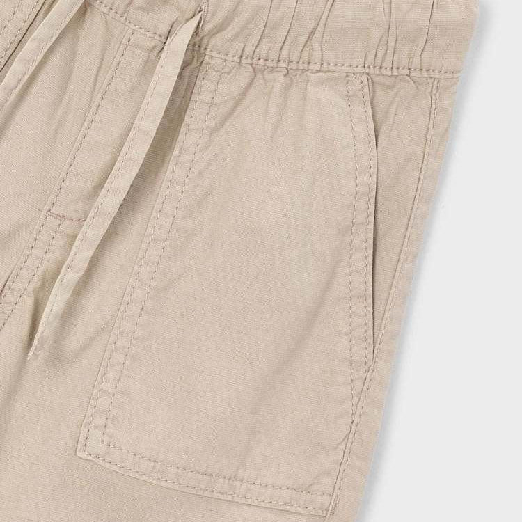 Close-up of beige shorts with a pocket on a light gray background