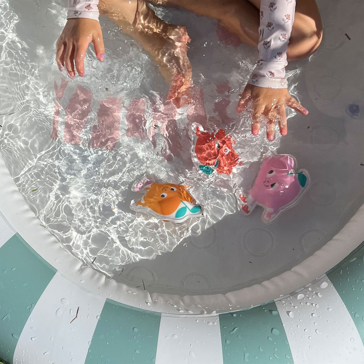 Children playing with colorful rubber ducks in a small pool.