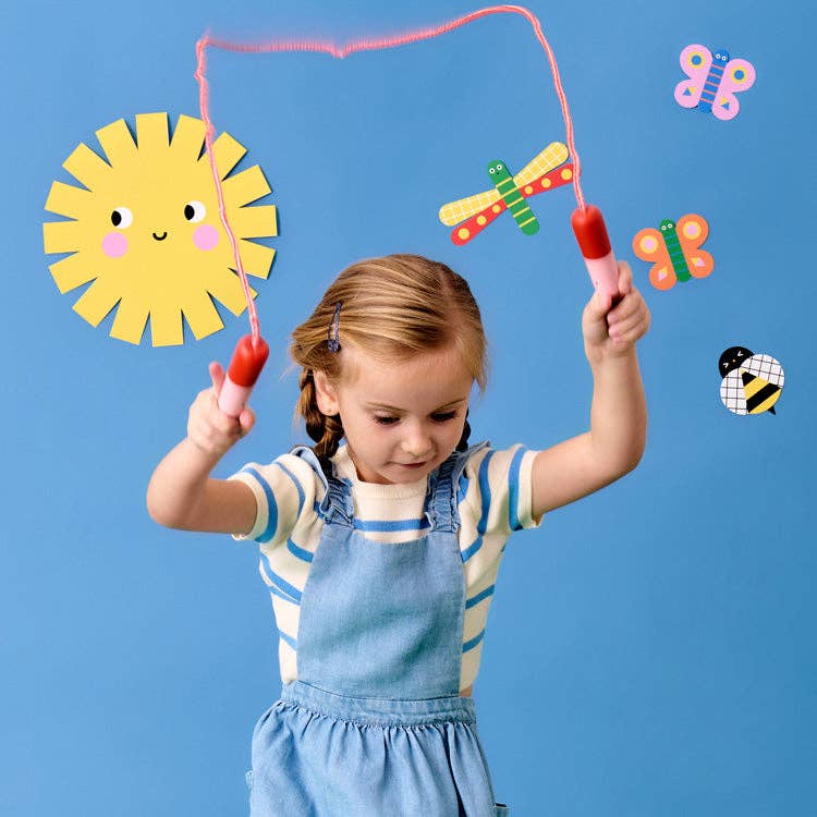 Child playing with colorful jump rope against a blue background