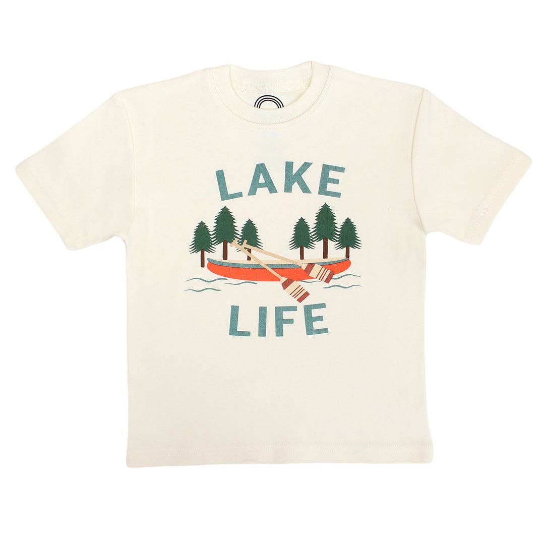 An off-white short-sleeve crewneck t-shirt featuring a graphic print of a red-orange canoe with a person rowing, surrounded by green pine trees and the words 'LAKE LIFE' in teal.