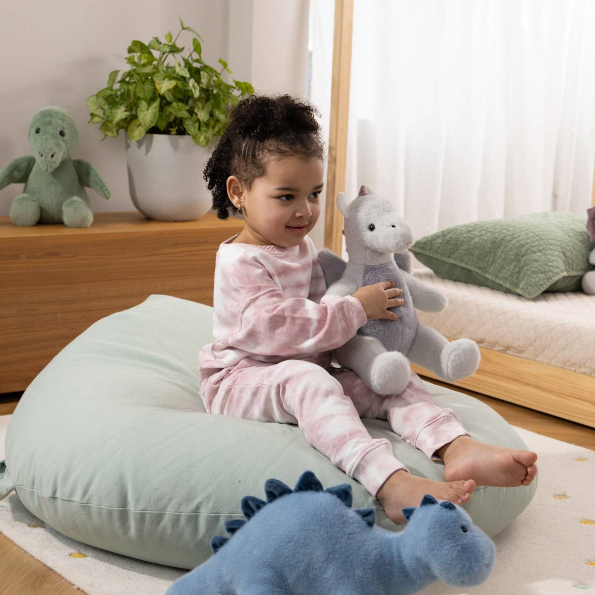 Child sitting on a bean bag with stuffed animals in a cozy room