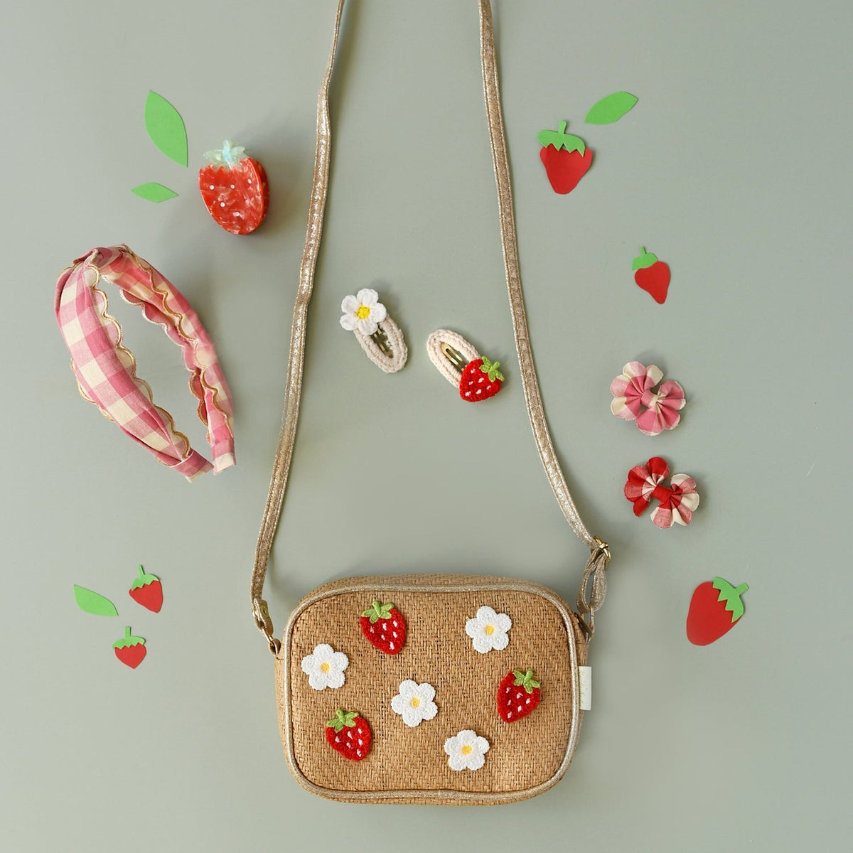 Woven handbag with strawberry and flower decorations on a light gray background