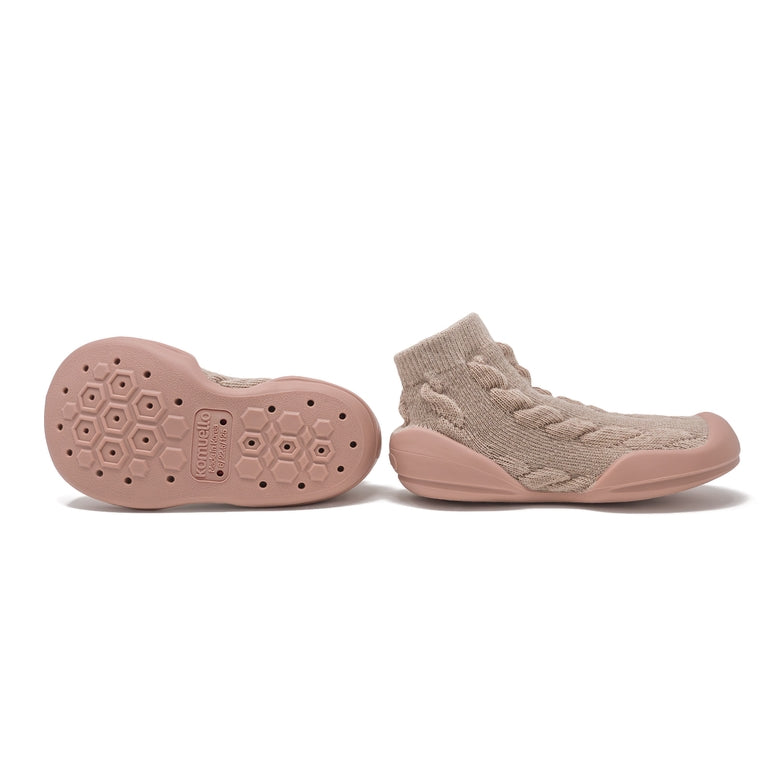 A pair of toddler knit slip-on shoes in a dusty pink and beige colorway, showing the side profile and the textured honeycomb-patterned outsole.