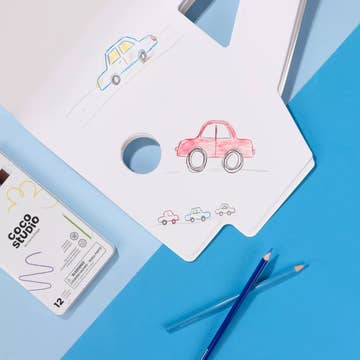 A white hand-drawn sketchbook with simple car illustrations, placed on a blue background with a pencil case, colored pencils, and a pen.