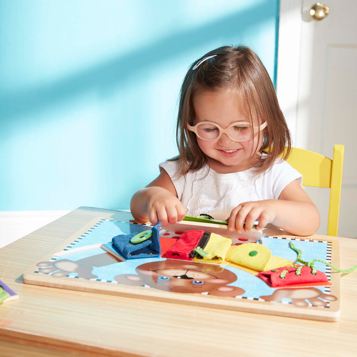Child with glasses playing with a puzzle at a table