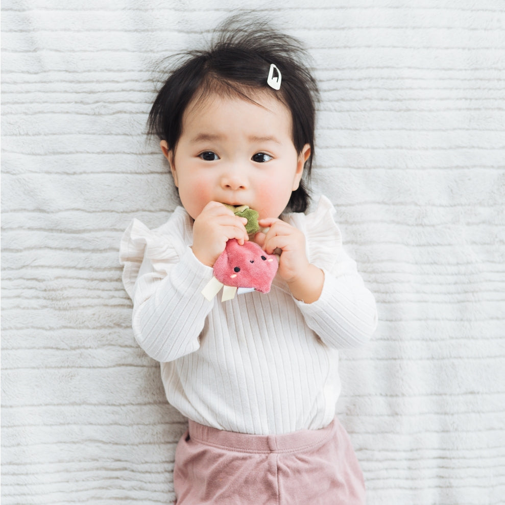 Child holding a pink toy against a textured white background