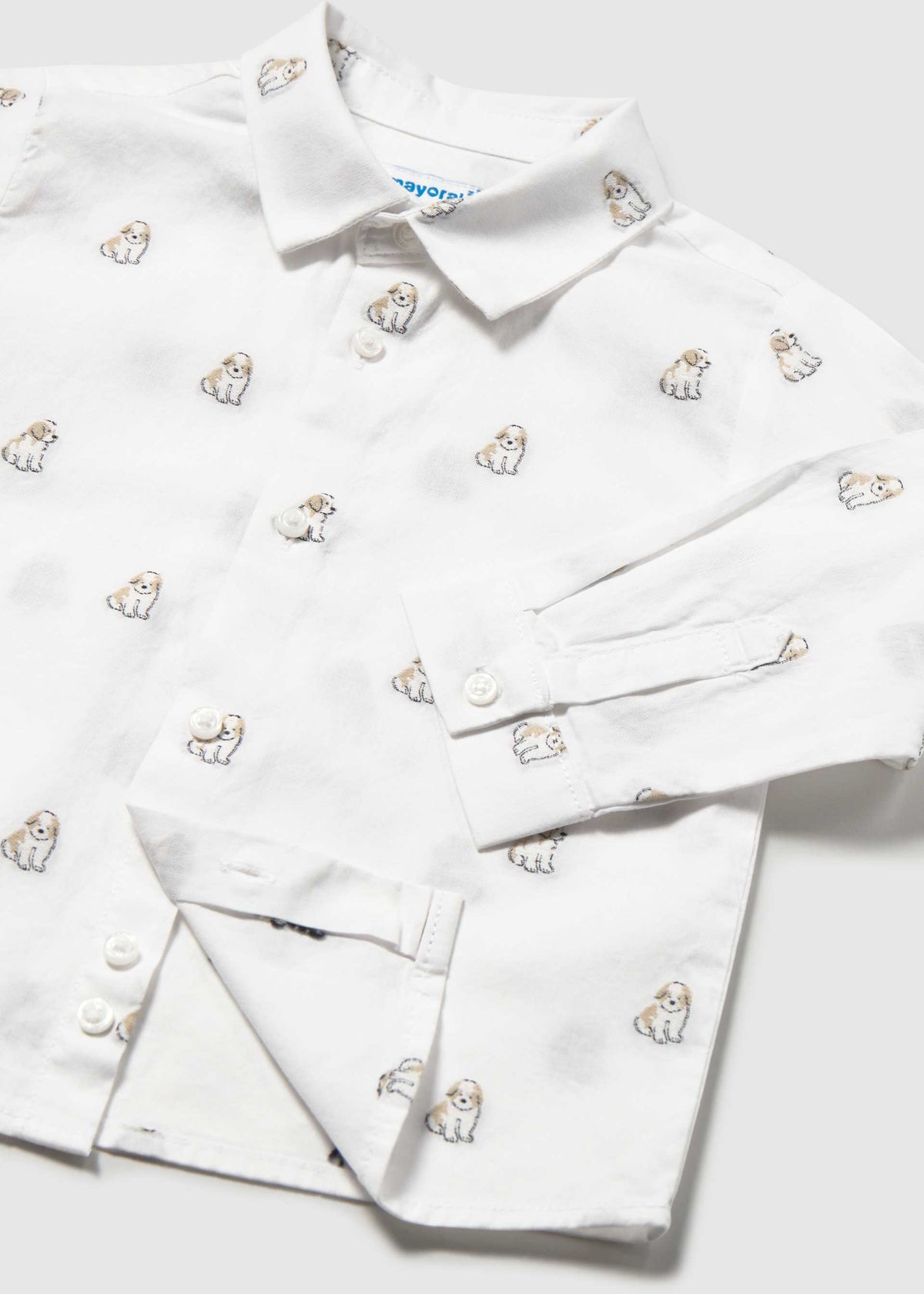 A white long-sleeve button-up shirt with an all-over embroidered pattern of small dogs, shown folded on a light gray background.