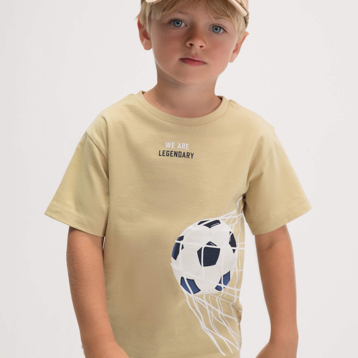 Child wearing a beige t-shirt with a graphic design on a plain background