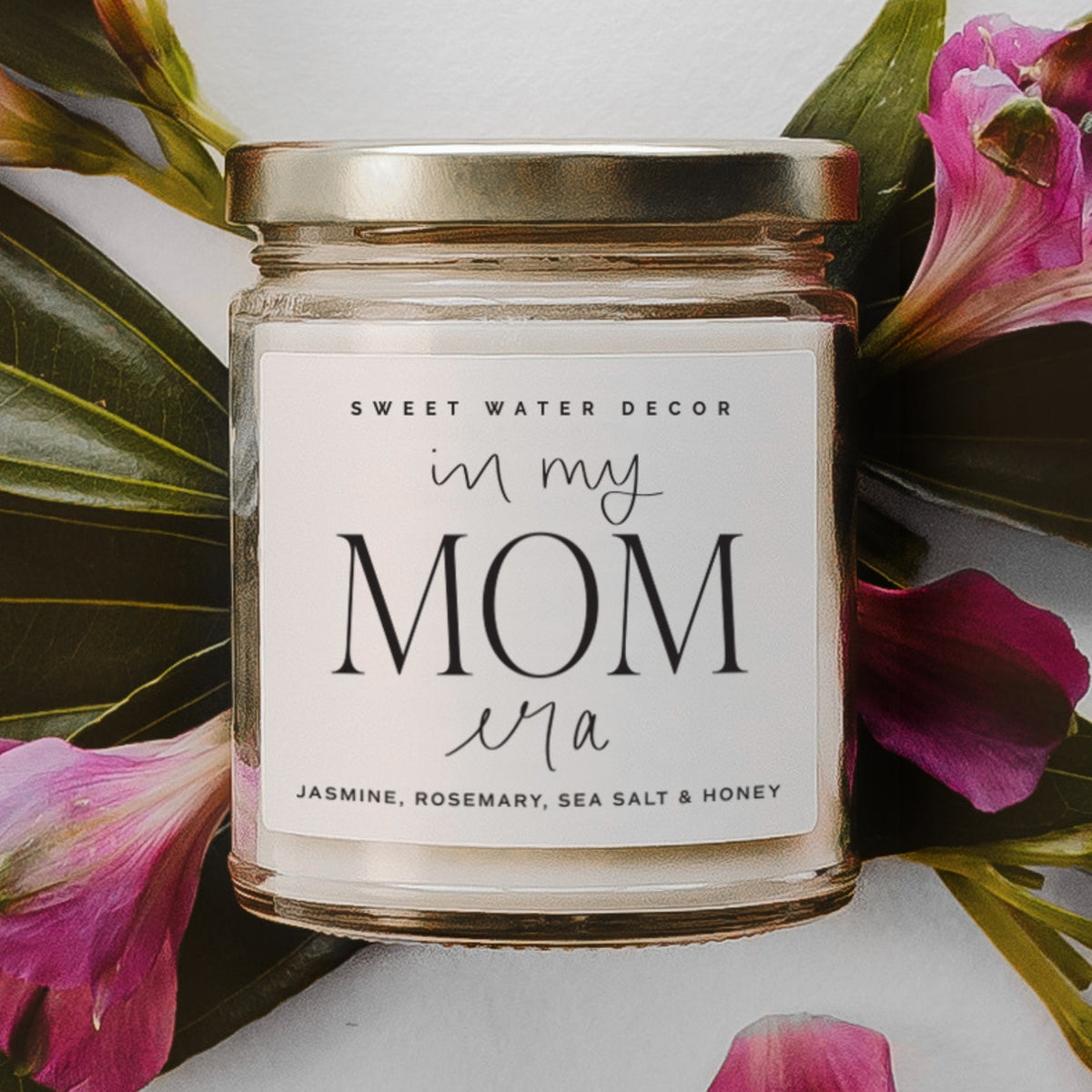 Candle jar with 'Sweet Water Decor' label surrounded by pink flowers