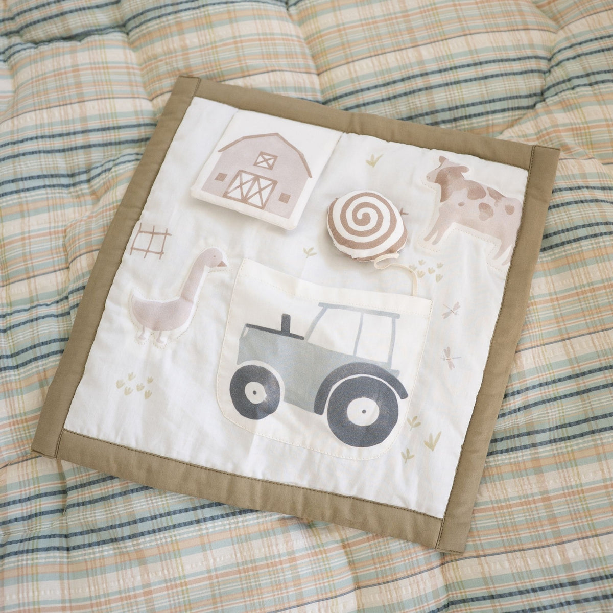 Decorative pillow with farm-themed illustrations on a plaid fabric background