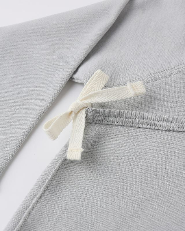 Close-up of a gray garment with a white ribbon tie on a light gray background