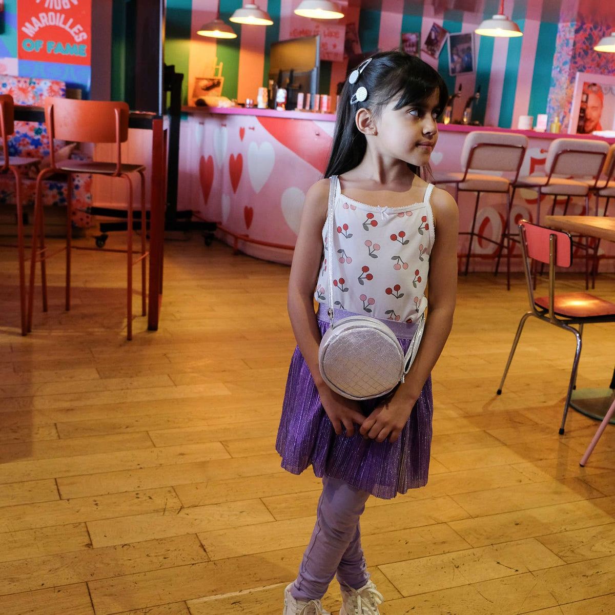 Young girl in a colorful indoor setting holding a small round object.