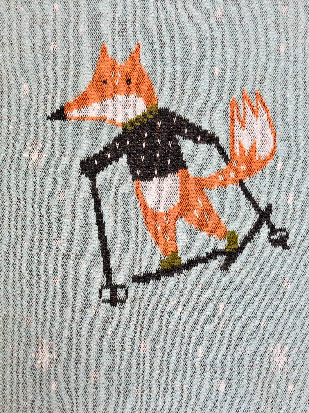 Cross-stitched design of a fox skiing on a textured fabric background