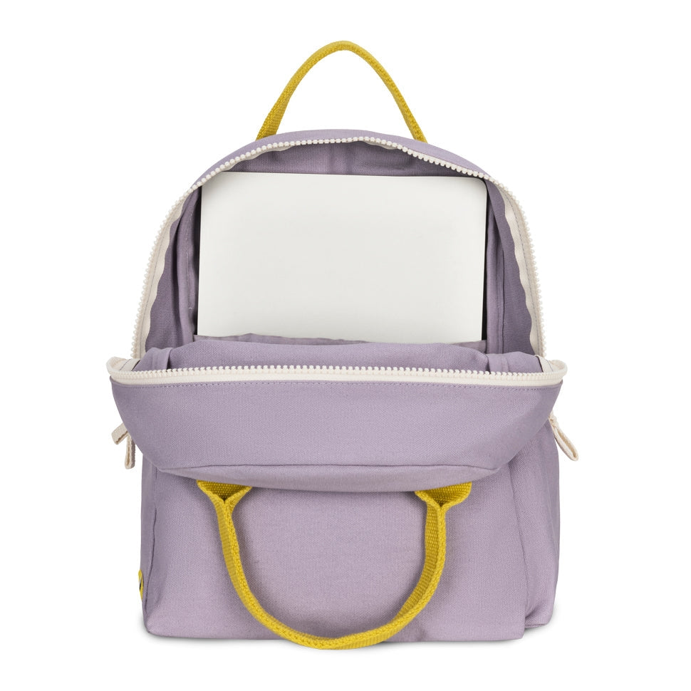A lavender purple backpack shown open, revealing a white laptop inside. The backpack features bright yellow handles and zipper pulls, and is photographed against a clean white background.