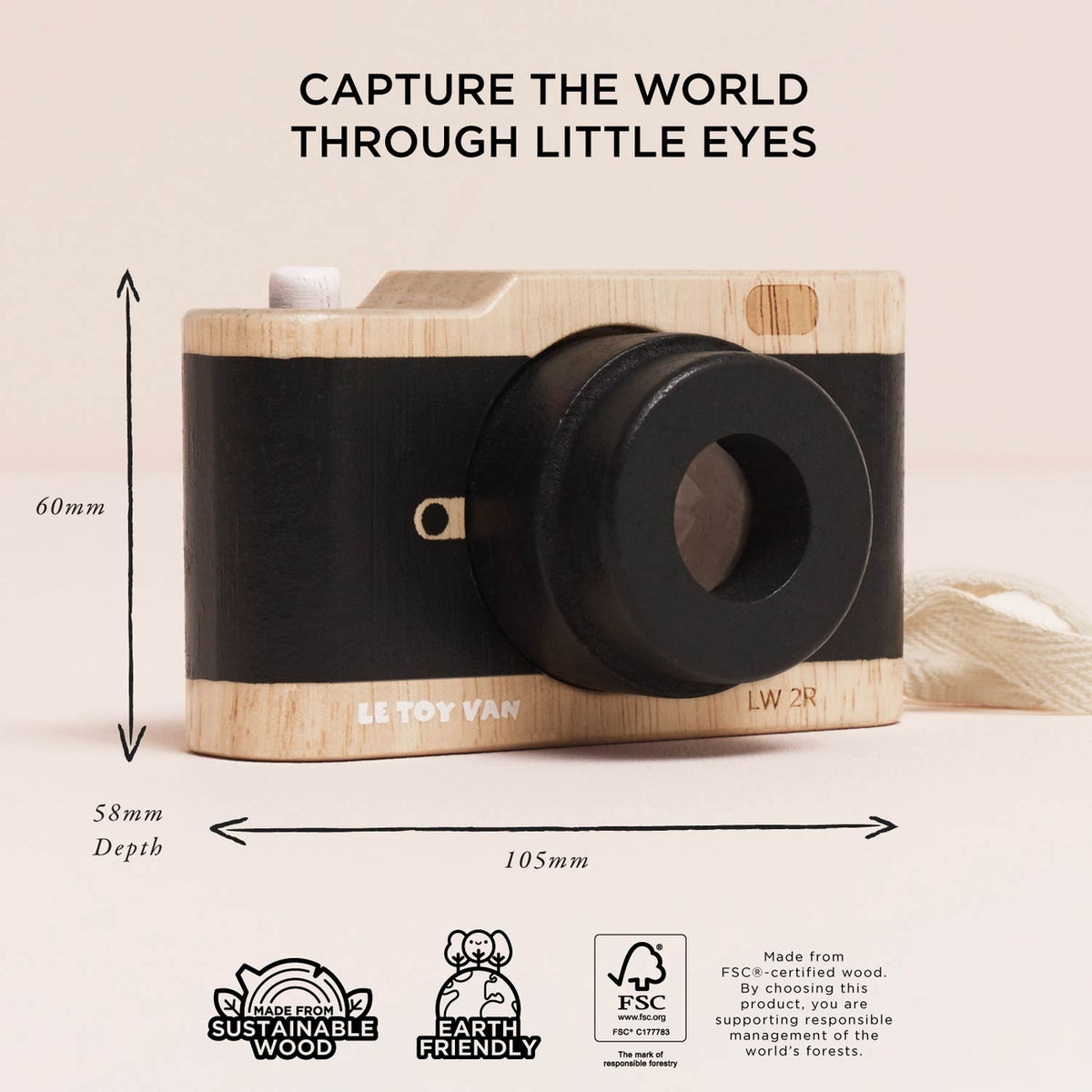 A wooden toy camera with a black faux-leather body and black lens, shown with dimension arrows and text indicating 60mm height, 58mm depth, and 105mm width. The top of the image reads 'CAPTURE THE WORLD THROUGH LITTLE EYES' and the bottom includes sustainability and eco-friendly badges.