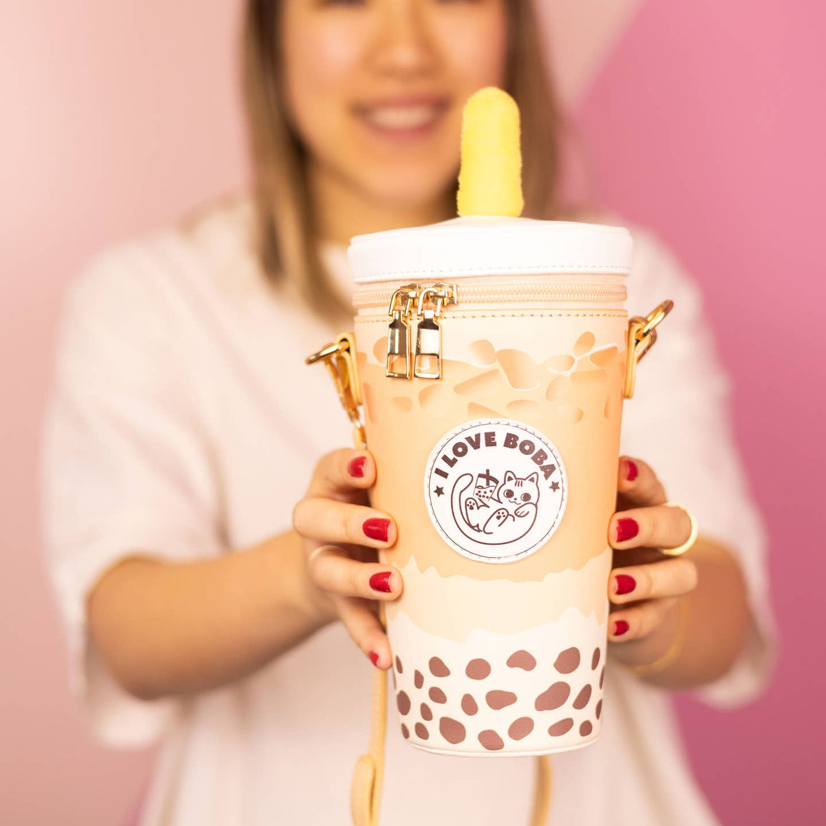 Person holding a bubble tea with a pink background