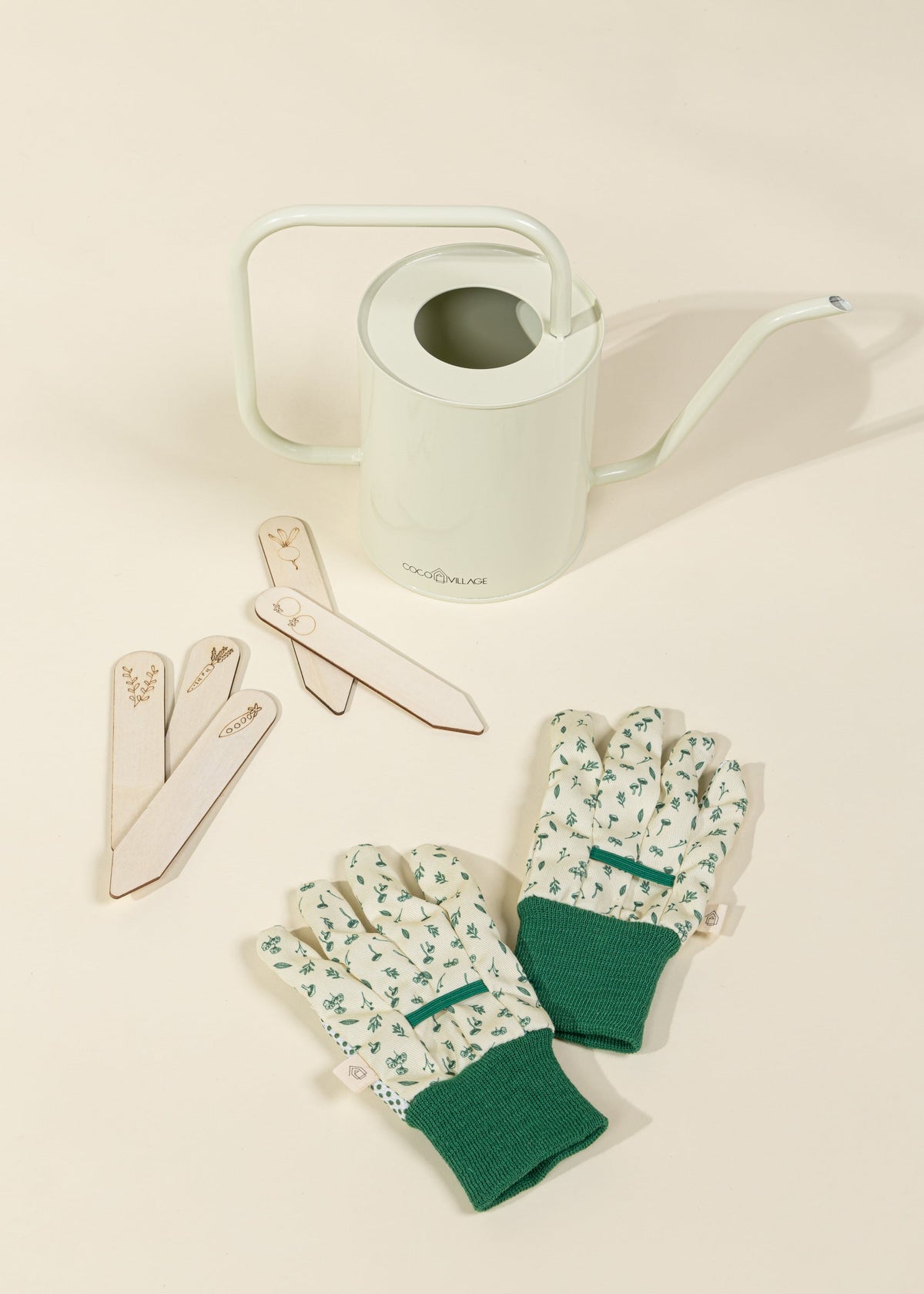 Gardening tools including gloves, labels, and a watering can on a light background