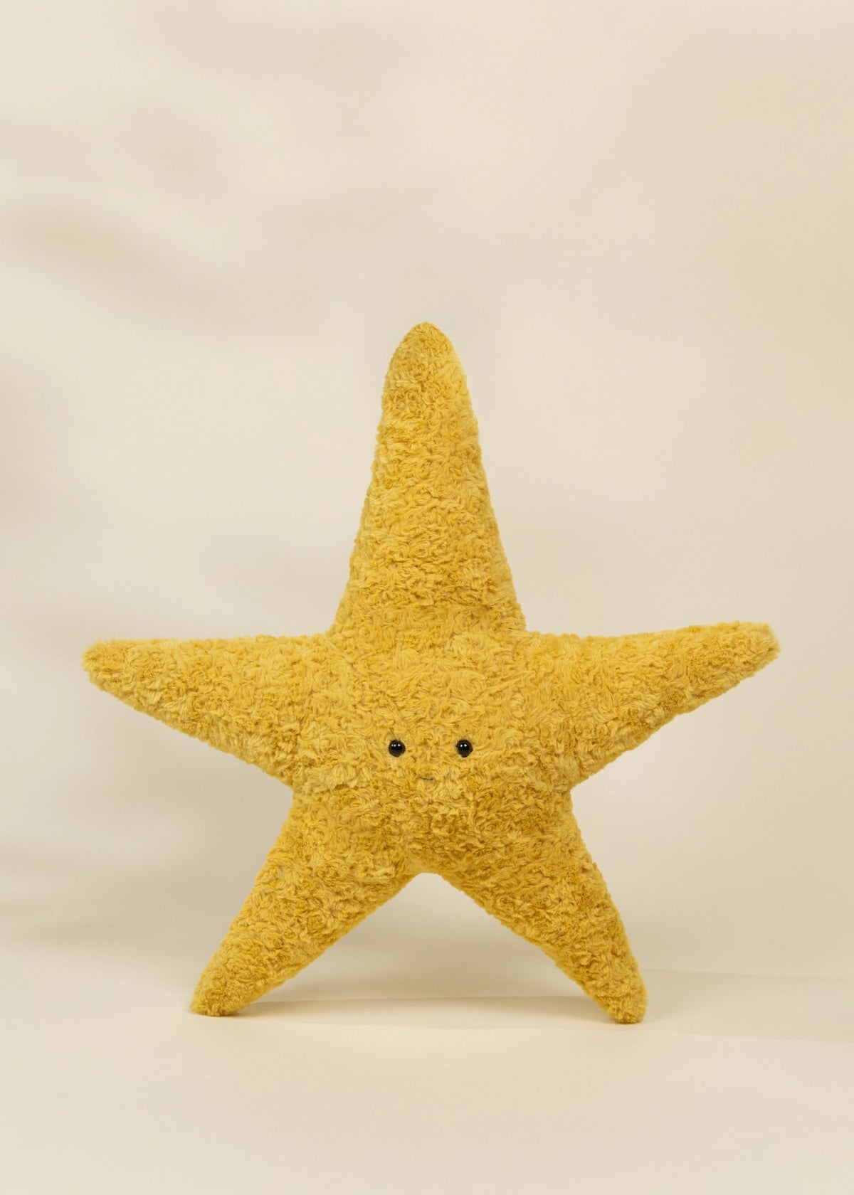 Yellow star-shaped plush toy on a beige background