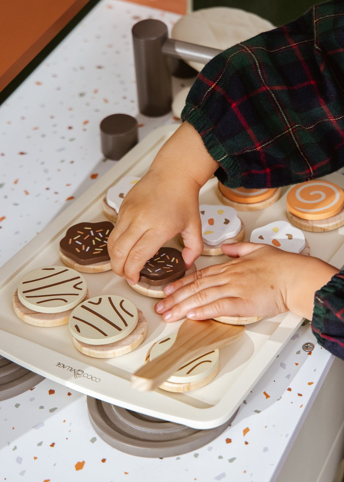 Hands decorating cookies on a baking tray with various cookie cutters.