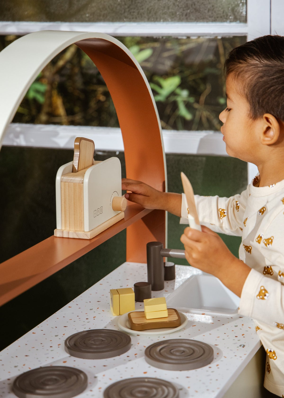 Child playing with a wooden toy kitchen set outdoors