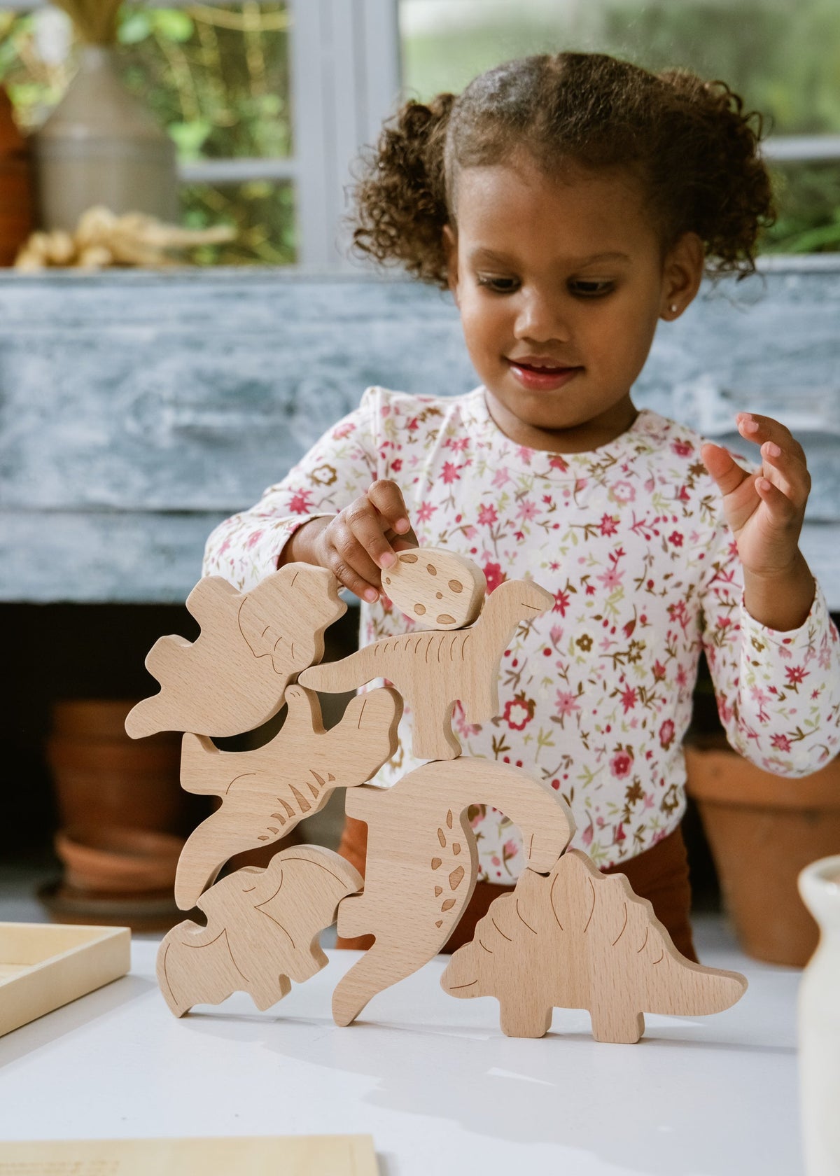 Child playing with wooden dinosaur toys on a table