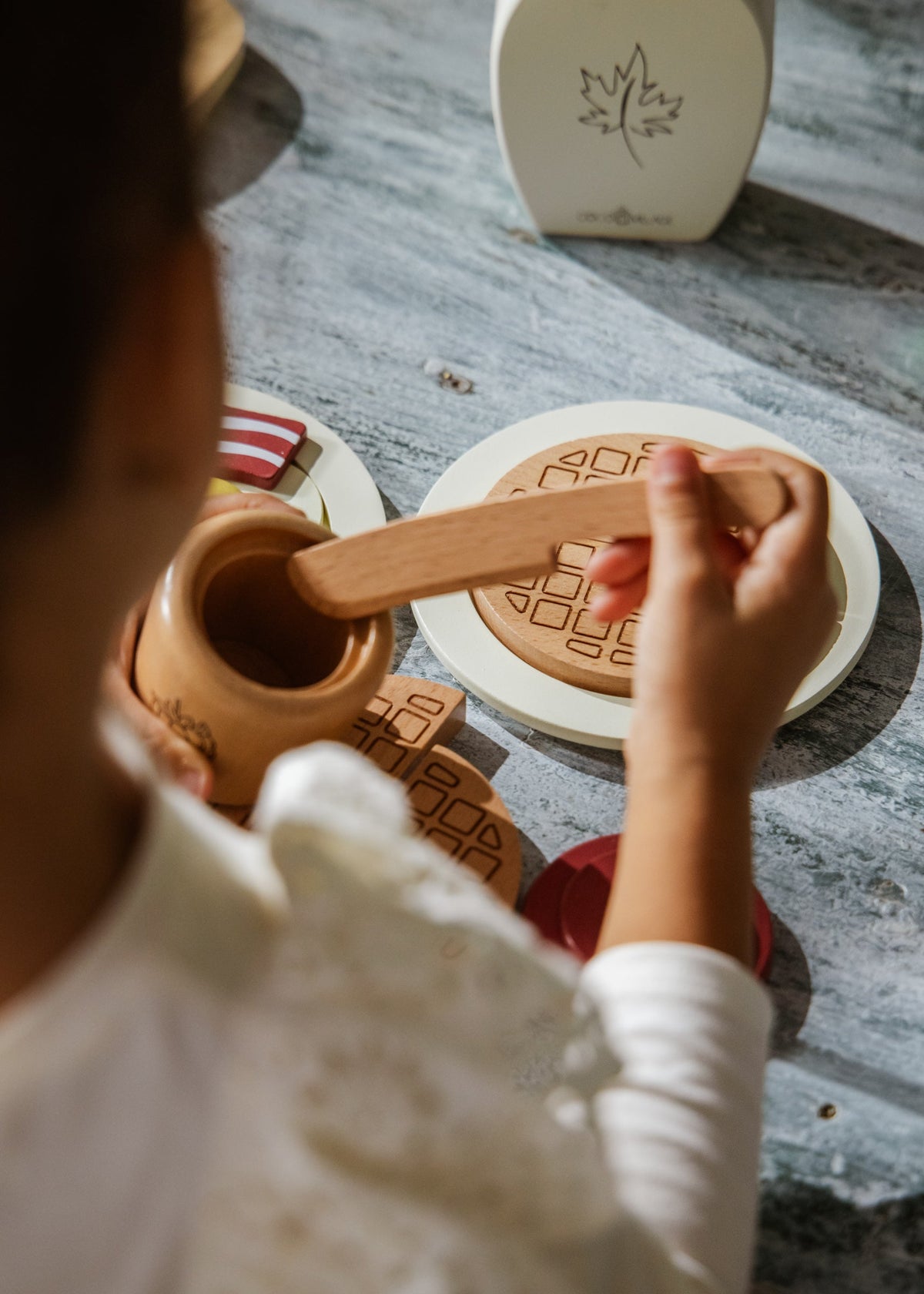 Person using a wooden tool on a ceramic pot with a blurred background