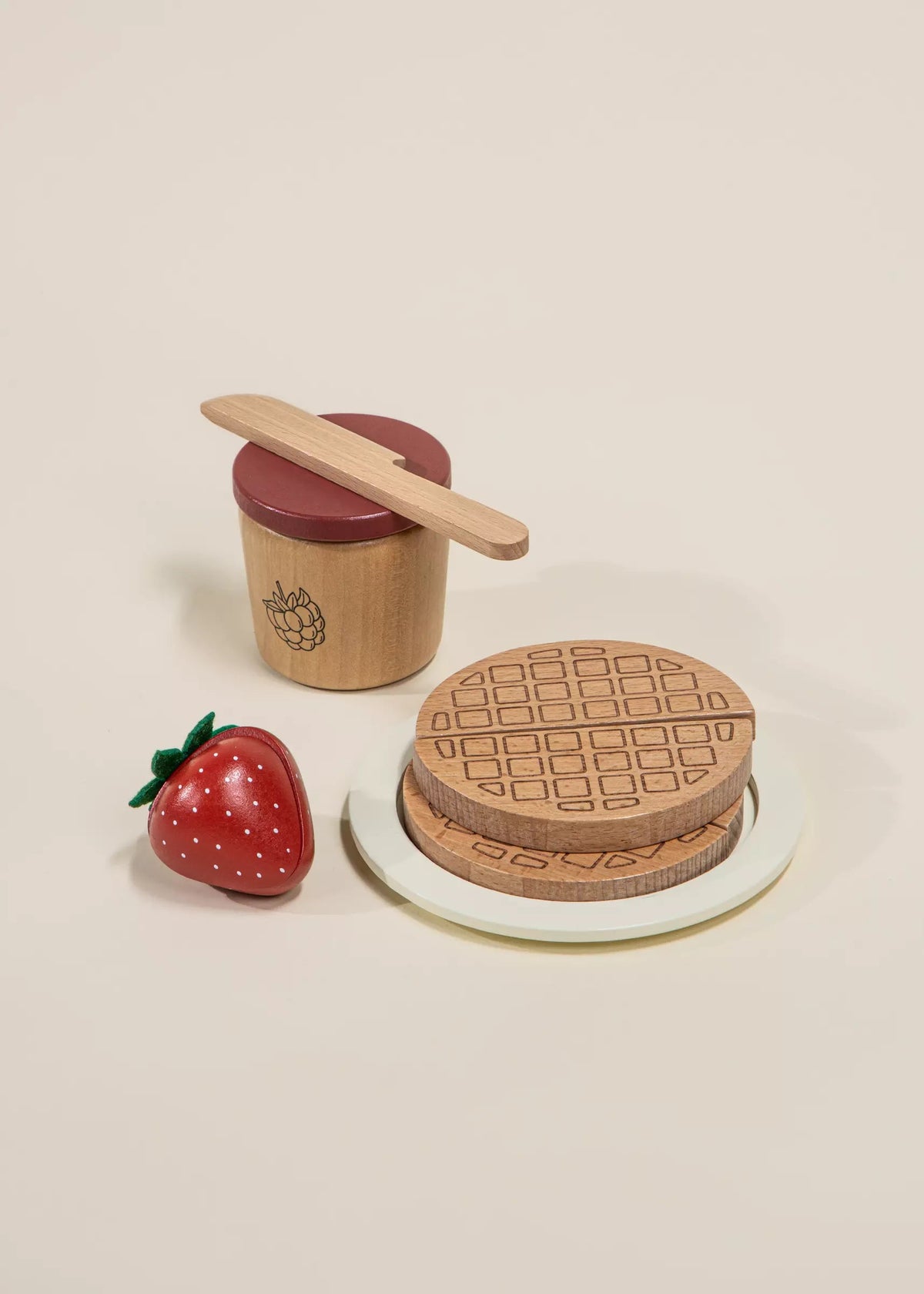 Wooden toy set with a waffle, strawberry, and container on a beige background
