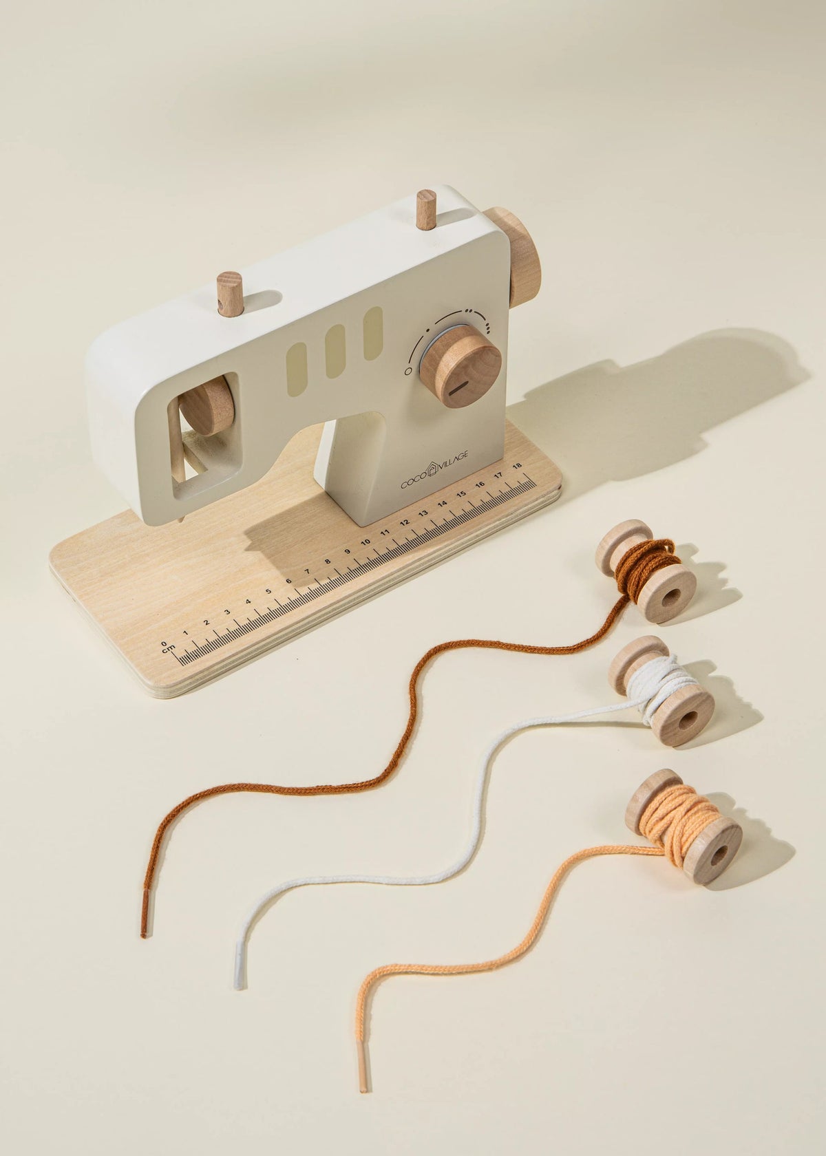 Toy sewing machine with spools of thread on a beige background