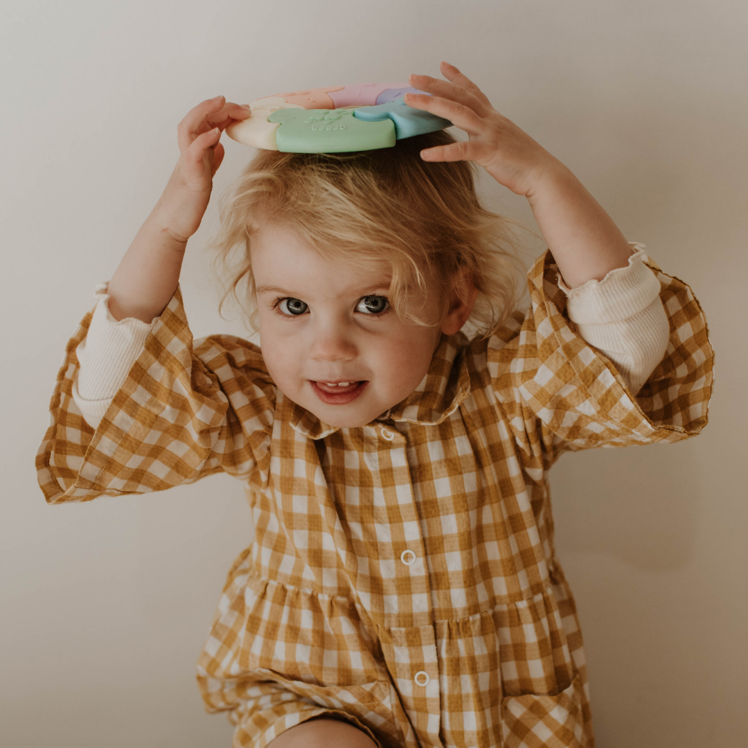 Child wearing a yellow checkered dress with a plain background