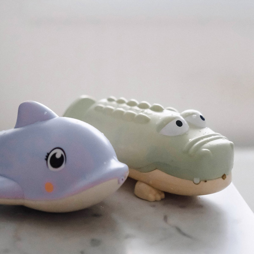 Toy crocodile and toy dolphin on a marble surface with a light gray background
