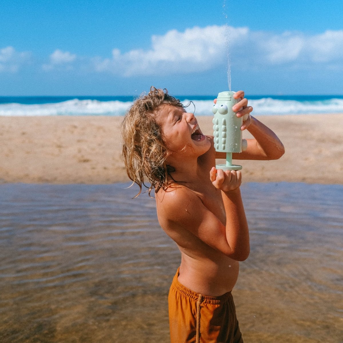 Child playing with a green toy at the beach